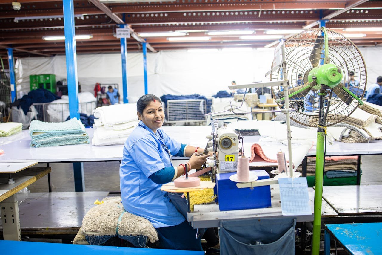A female textile worker busy sewing fabrics in a bright and organized factory setting.